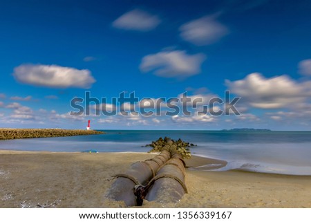 amazing  view  ,lght house on a breakwater and pipe at Chendering Beach, located in Terengganu, Malaysia. long exposure photography,Soft focus effect.