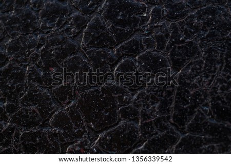 Background texture. Black shiny surface with many cracks. Dark black with gray background with interesting relief. Abstract background. Macro photo. 