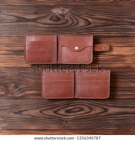 Two red color handmade leather wallets on wooden textured background. Up to down view. Wallet stock photo.