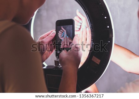 Young woman taking photo of manicured woman hand. Taking photo of nails in beauty salon.