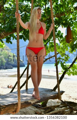 blonde in red swimsuit on beach swing