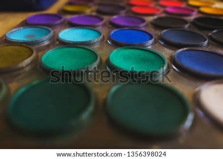 Pastel colors in a plastic round palette. Drawing supplies. Multi-colored paints and crayons. Top view and soft focus.