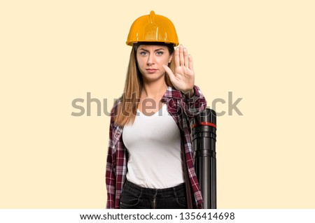 Architect woman making stop gesture denying a situation that thinks wrong over isolated yellow background