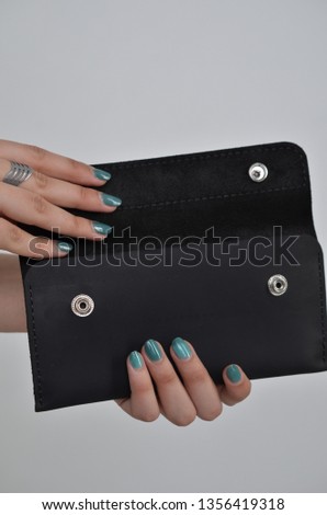 a leather wallet that is fully visible on the photo in the hands of women