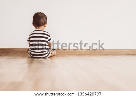 Back view of Little baby boy sitting alone and watching smartphone.Vintage tone.