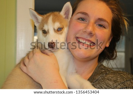Woman holding a husky puppy in the house