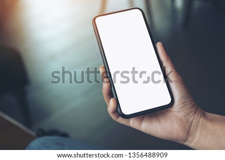 Mockup image of a woman's hand holding black mobile phone with blank desktop screen  Royalty-Free Stock Photo #1356488909