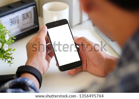 Mock up smartphone of hand holding black mobile phone with blank white screen. Royalty-Free Stock Photo #1356495764