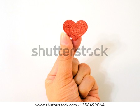 Women's hand holding a red heart on white background. Asian hand. Love and care concept.