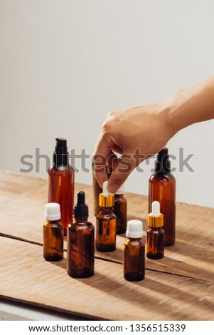 Essential oils bottles on wooden desk with candlelight beside. Spa wellness set.