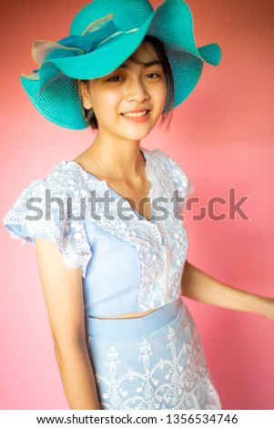 Beautiful Asian teenager girl wearing blue vintage dress with the blue hat and smile.Pink isolated background