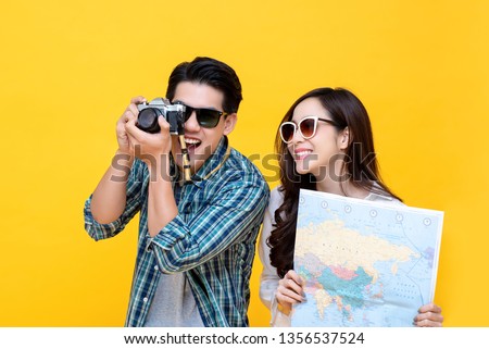 Portrait of a young happy smiling asian tourist couple in casual attire enjoying their summer vacation getaway together in yellow studio background