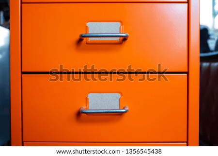 Filing cabinet with closed drawer, 2 brown cards for write letter, Orange metal colour, Administration and storage concept, closeup & Macro shot