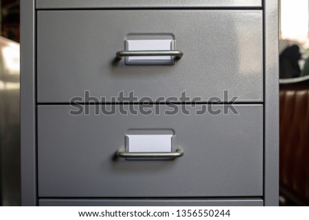 Filing cabinet with closed drawer, 2 white cards for write letter, Grey silver metal colour, Administration and storage concept, closeup & Macro shot