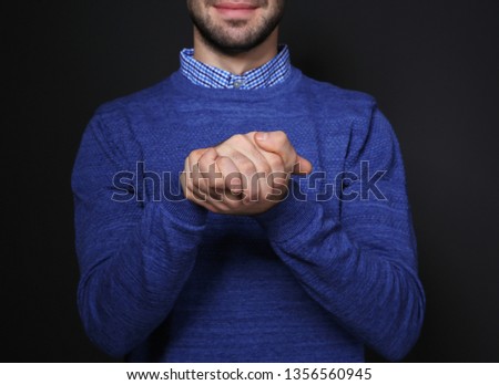 Man showing BELIEVE gesture in sign language on black background, closeup