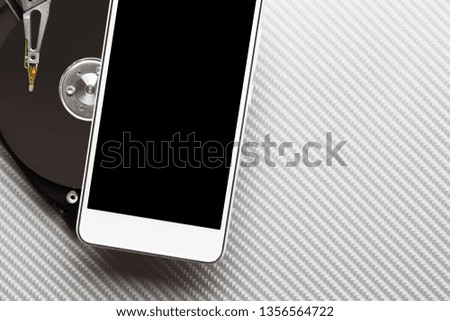 Hard disk plate and cellphone on carbon background