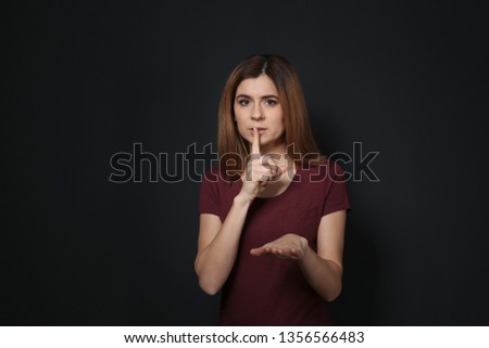 Woman showing HUSH gesture in sign language on black background