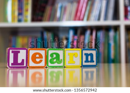 Alphabet blocks spelling the word learn in front of a bookshelf