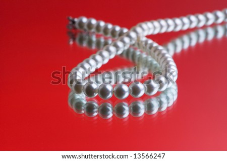 Pearl necklace on the red reflective background