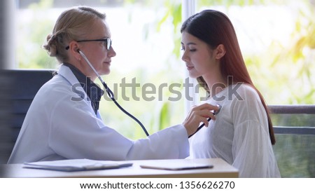 Senior female doctor checking examining a woman by stethoscope in office hospital.

