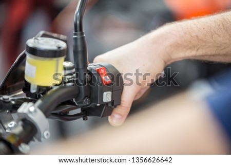 Hand rider on handlebars turns the gas pedal. Motorcycle handlebar horns,start and stop switch . Close up.