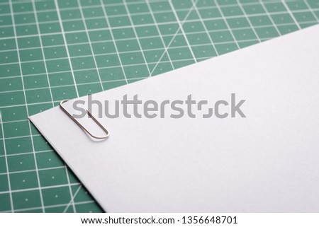 Paper clip on stack of papers lying on cutting mat