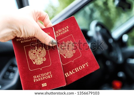 Russian passports in the hand of woman and blur car background. Concept of travel abroad by car for Russian citizens