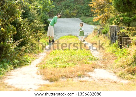 This is a picture of a mother and daughter wearing a green dress playing happily in the park at sunset.