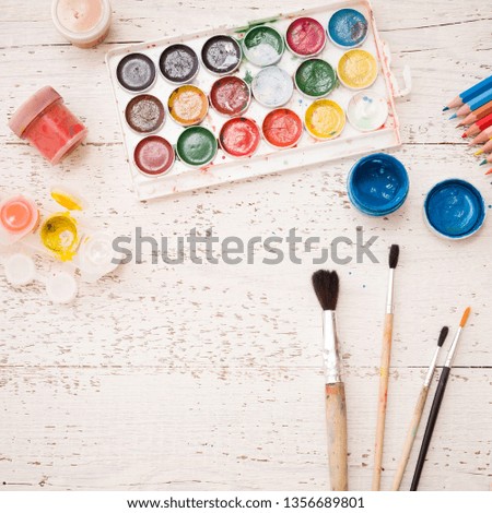 Closeup of watercolors, paint brush and some art stuff on white wooden table. Creative ideas, creativity and early learning. Education concept.