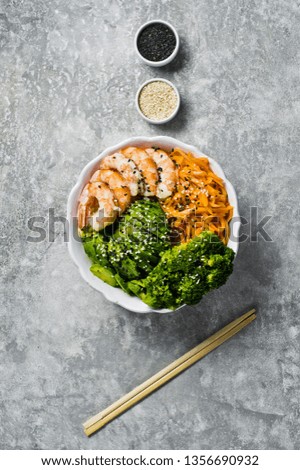 Buddha bowl with shrimps, avocado, carrot, brocoli and rice. Balanced food. Gray background, top view, space for text