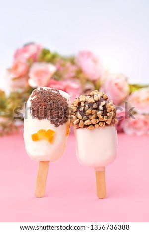 decorated ice cream popsicles on abstract pink background. ice cream in chocolate glaze and nuts. tasty sweet treats. symbol of love, romance. 