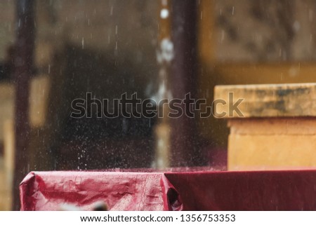 Summer terrace of the restaurant in the rain. Wet the table with a Burgundy tablecloth. A spray of water. Rainy weather.