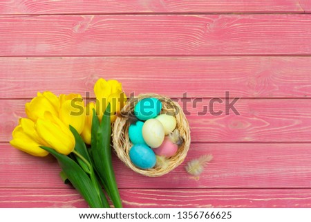 easter, holidays, tradition and object concept - close up of colored eggs and tulip flowers over wooden boards background