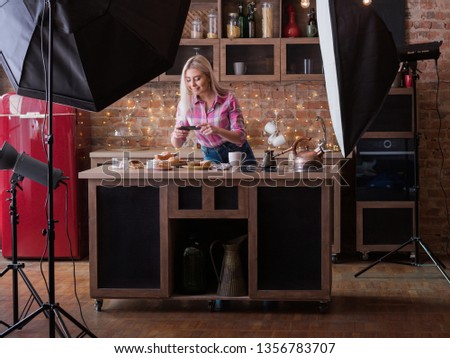 Food blogger. Backstage photography. Female lifestyle and business. Young woman with smartphone shooting pastries.