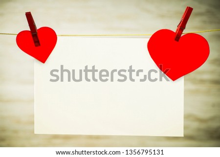 A card and a red heart hanging on a string, fastened with red buckles