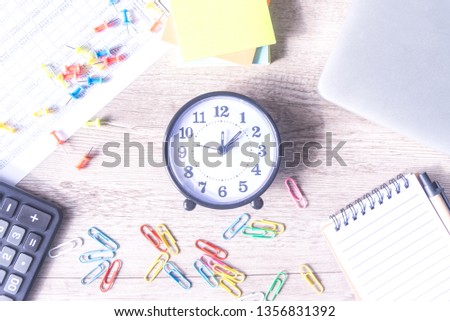 Time management concept. Composition with alarm clock on wooden table with laptop computer, stationary and calculator, top view above