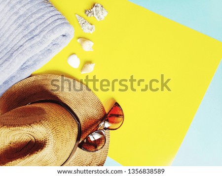 Summer holiday flat lay composition photography. Stylish vintage wicker hat, trendy sunglasses, a soft purple towel and shells on a yellow background. Beach relaxing photo