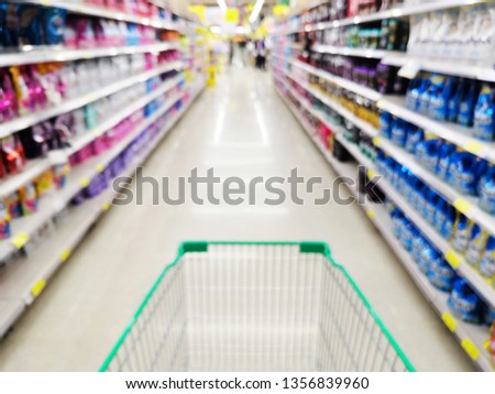 Supermarket aisle with empty red shopping cart,  In department store bokeh background.