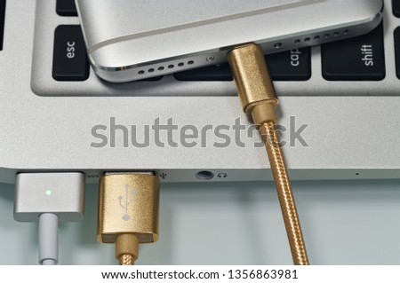 Connection smartphone with a usb cable to laptop. Close-up.