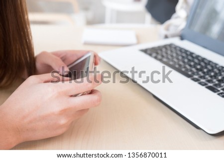 Woman use smartphone - working freelance in the coffee shop with laptop on desk