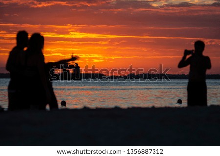 High contrast silhouettes of people on the beach during the sunset. They taking photos of each other and having fun  - Isla Mujeres - Mexico.
