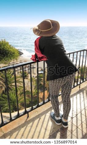photograph of a tourist in the viewpoint of the balcony of Europe, Nerja, Málaga, Andalusia, Spain, Woman, girl, are hat, pamela, looking at the sea and the Calahonda, beach