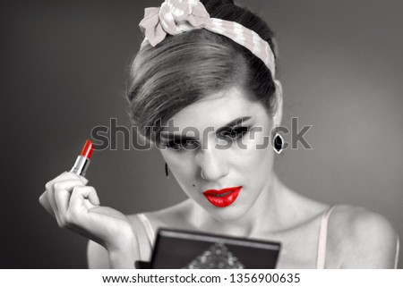 Makeup materials and their uses girl in pin up retro style do makeup red lipstick. Black and white photo with red color lips accent.