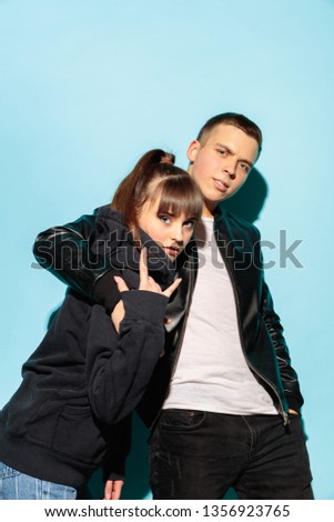 We are friends. Close up fashion portrait of two young cool hipster girl and boy wearing jeans wear. Studio shot of two models having fun and making serious faces.
