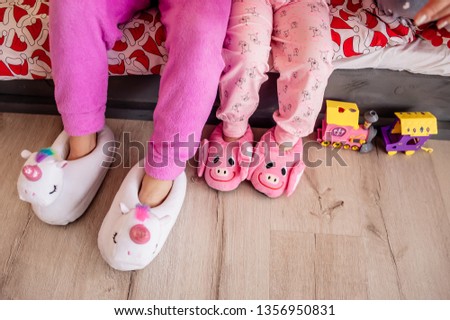 a pair of fluffy white and pink unicorn and piggy slippers on a wooden floor