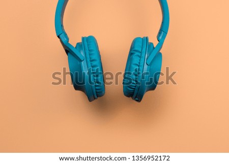 Photo of stylish modern blue cyan headphones over beige background