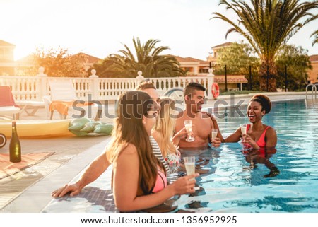 Group of happy friends making a pool party at sunset - Millennial young people laughing and having fun drinking champagne in the pool - Friendship, holidays and summer youth lifestyle concept