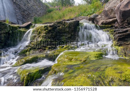 Natural cascading waterfall on a large creek flowing through a city of Tronfheim