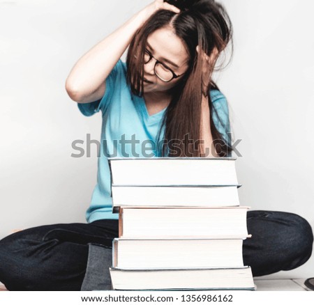 Asian girl Wearing blue t-shirts, glasses, reading books And a notebook with a pile of books and a cup of coffee on gray background, Soft focus
