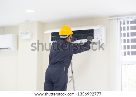 The mechanic Technician are Repairing Air Conditioner in room. Royalty-Free Stock Photo #1356992777